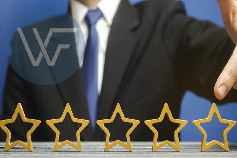 A person in a suit placing a gold star on a table among four other gold stars.