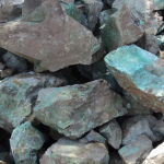 A collection of copper ore rocks with a greenish patina, showcasing their natural texture and color.