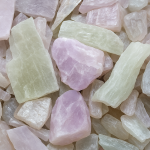 Collection of various natural gemstones in shades of pink and green, including rough and polished pieces.
