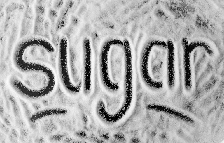 The word 'sugar' written in powder, providing a sweet theme in a minimalist photo.