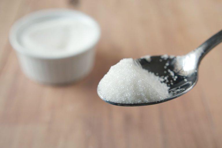 A close-up shot of granulated sugar on a spoon, highlighting texture and shine.