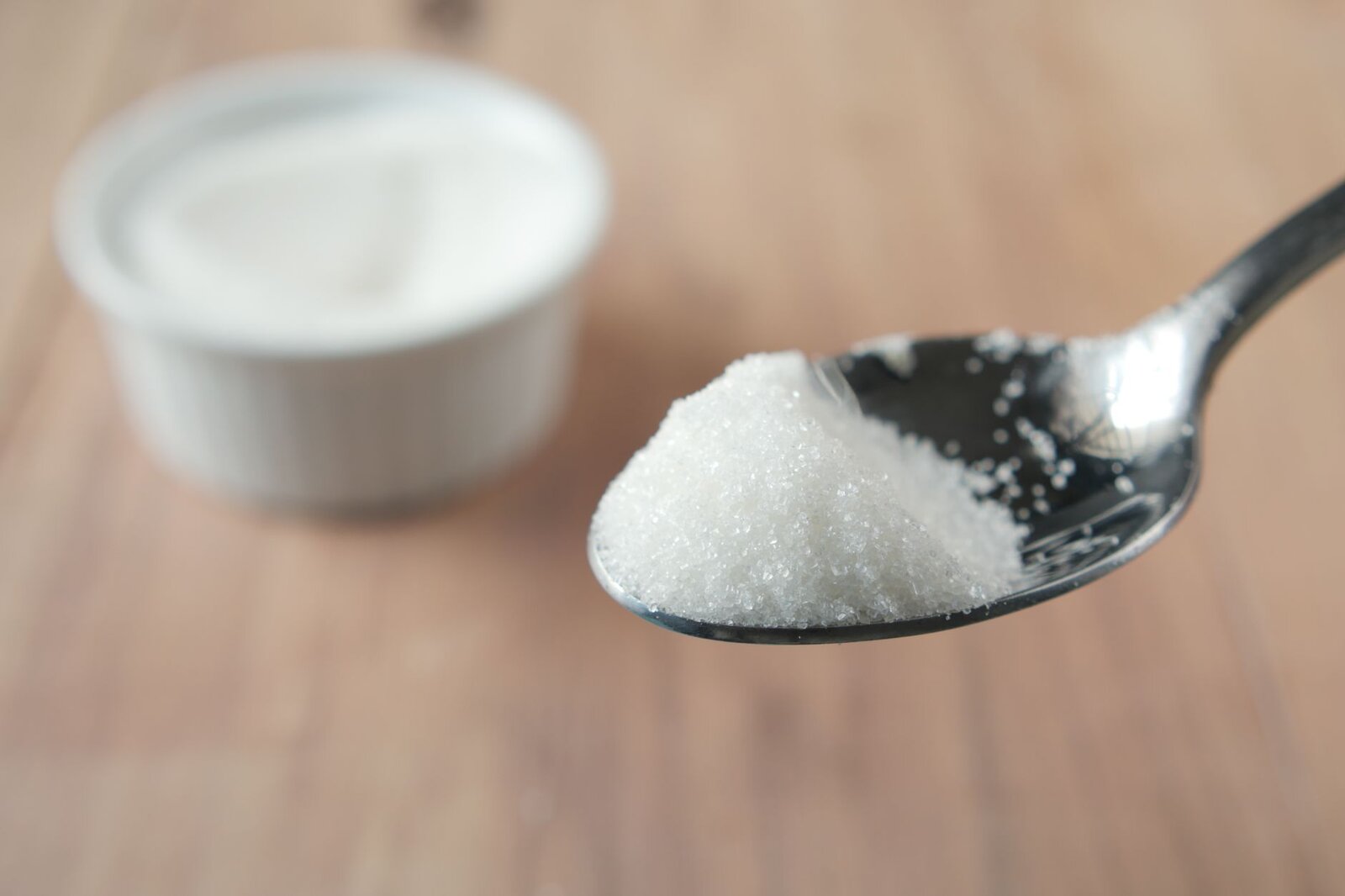A close-up shot of granulated sugar on a spoon, highlighting texture and shine.