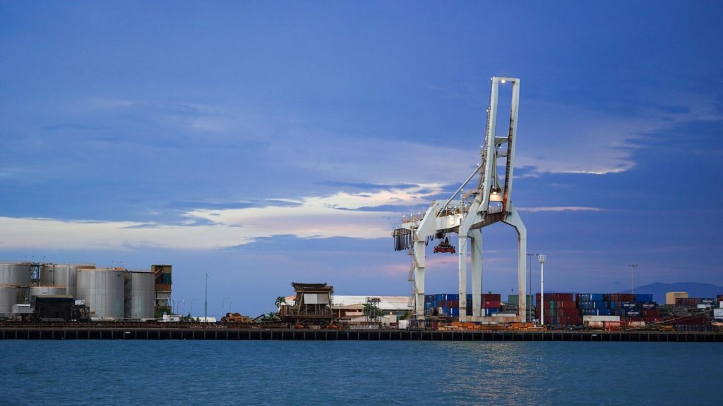 A serene view of an industrial port with cargo cranes and containers at twilight.