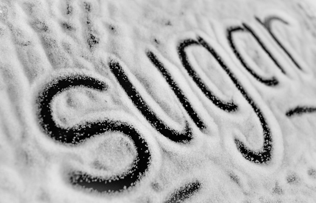 Photograph of the word 'sugar' written in fine granules for a textured effect.