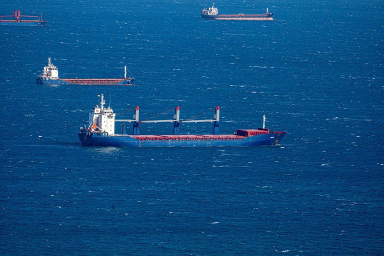 Aerial view of multiple cargo ships navigating through the vast blue ocean, capturing maritime commerce.