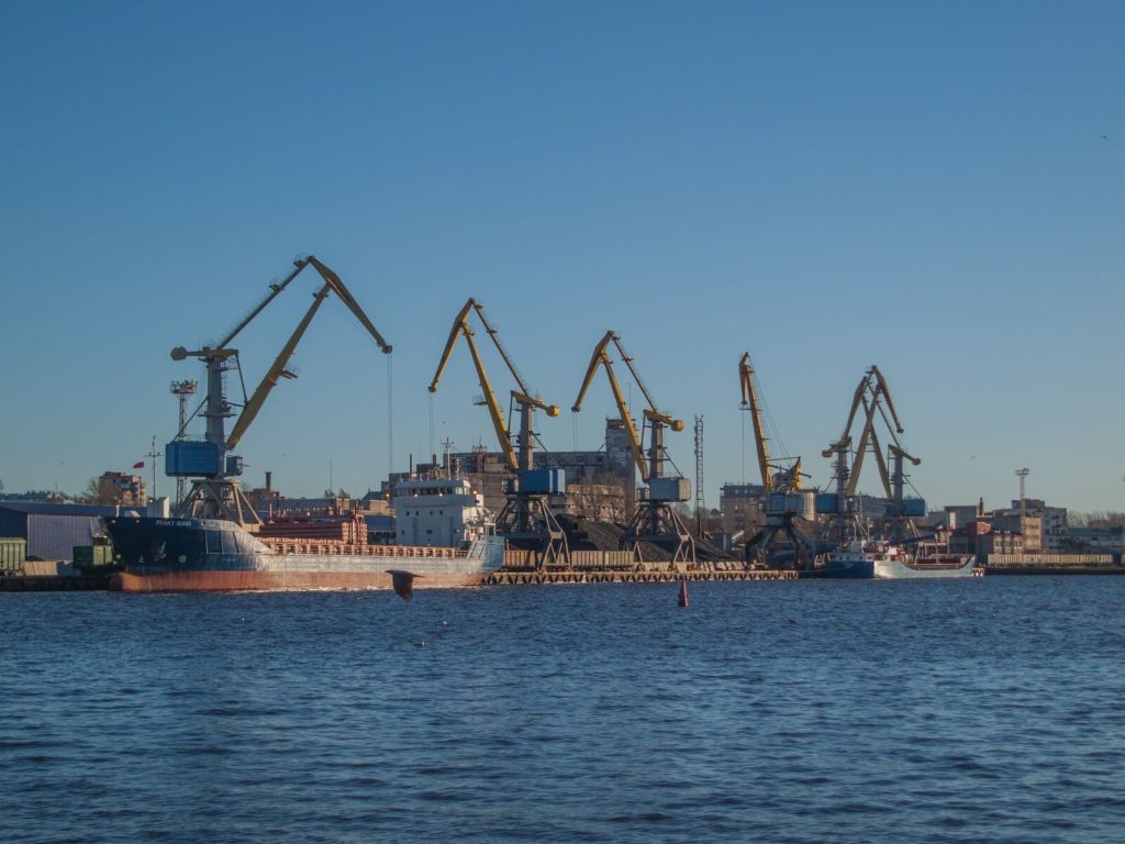 Image of an industrial shipyard with cranes and ships on a sunny day.