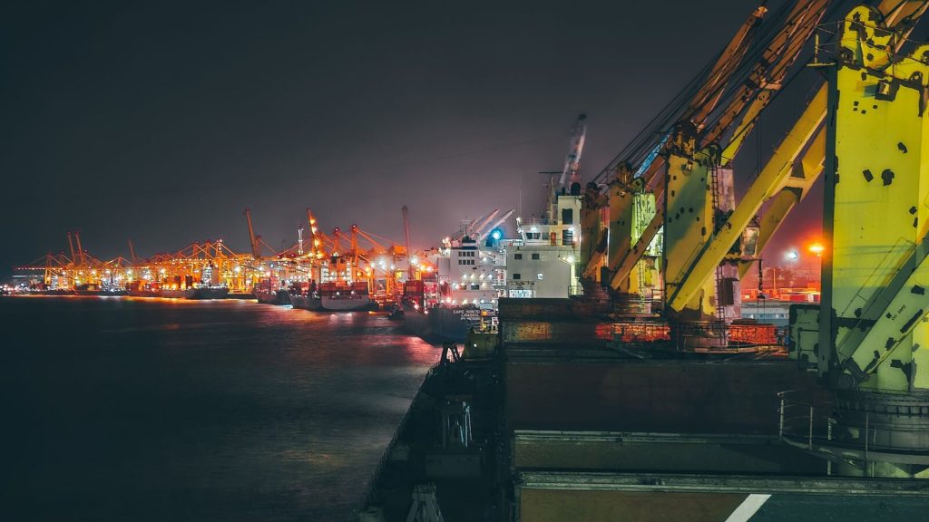 Cargo ships illuminated at night in a bustling harbor showcasing logistics and maritime activity.