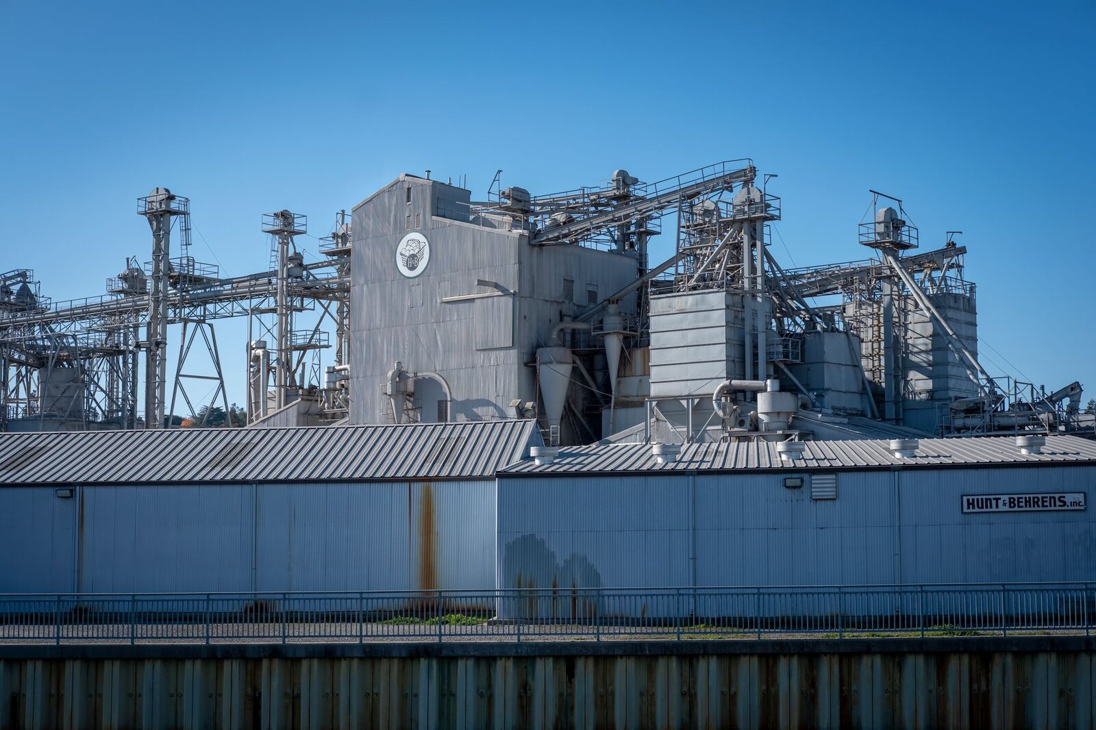 A large industrial facility showcasing metal structures and machinery under a clear blue sky.