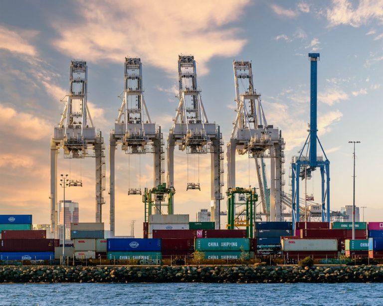 A vivid illustration of port logistics with cranes and shipping containers under a striking sky.