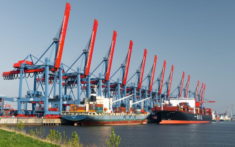 Container ships docked at Hamburg Container Terminal under clear skies, showcasing global trade.