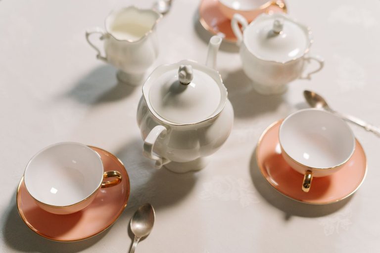 A vintage porcelain tea set featuring teapot, cups, saucers, and sugar bowl on a white surface.
