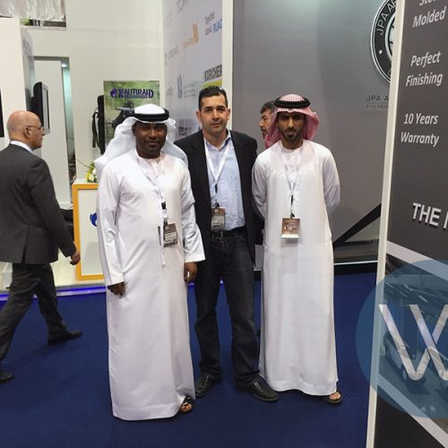 Three men wearing traditional attire posing together at an exhibition event.
